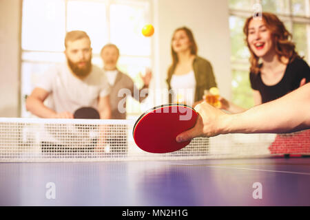 Group of happy young friends playing ping pong table tennis Stock Photo