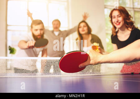 Group of happy young friends playing ping pong table tennis Stock Photo