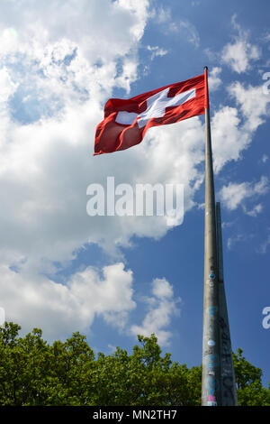 Swiss flag waveing over sky background on top of a hill in Neuchatel, Switzerland Stock Photo