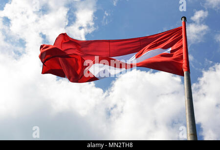 Swiss flag waveing over sky background on top of a hill in Neuchatel, Switzerland Stock Photo