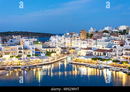 View of town and harbour at dusk, Agios Nikolaos, Lasithi Region, Crete (Kriti), Greece Stock Photo