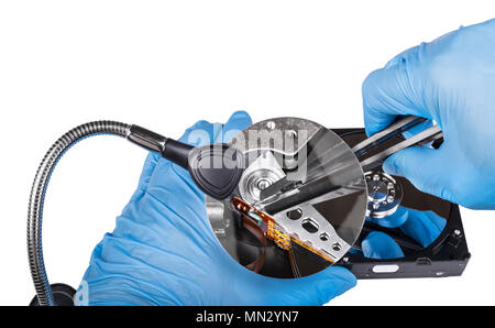 Fix of hard disk drive. Diagnostics close-up. Hands in blue gloves. Zoom of data recovery by magnifying glass. Open digital storage device, tweezers. Stock Photo