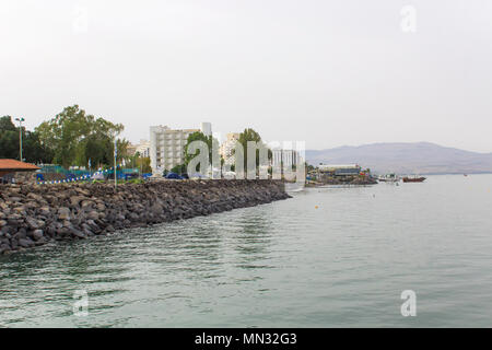 The calm glassy waters of the Sea of Galilee with moored boats in early evening on a hazy day in May 2018 Stock Photo