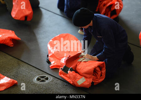 Coast Guard Seaman Brooke Baker-Rodriguez stows a survival suit Saturday, Aug. 26, 2017, following an abandon ship drill while the crew was in transit to the Arctic from Dutch Harbor, Alaska.    Baker-Rodriguez reported to the Coast Guard Cutter Healy earlier in August, and this deployment is her second time underway.    U.S. Coast Guard photo by Petty Officer 3rd Class Amanda Norcross Stock Photo