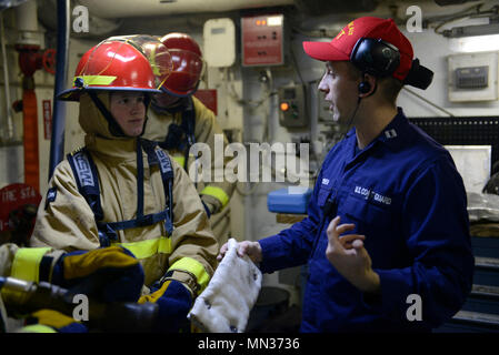 Coast Guard Seaman Brooke Baker-Rodriguez and several crew members listen as Lt. Kevin O’brien breaks down the fire response process Tuesday, Aug. 29, 2017, after conducting fire training aboard the Coast Guard Cutter Healy while transiting the southern Chukchi Sea.    At the same time as the training, other members around the ship were supporting scientific research missions, performing regular maintenance on one of the main diesel engines, and manning the multiple duty stations that keep the cutter running.    U.S. Coast Guard photo by Petty Officer 3rd Class Amanda Norcross Stock Photo