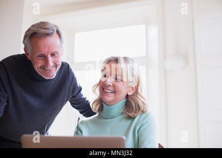 Smiling mature couple using laptop Stock Photo
