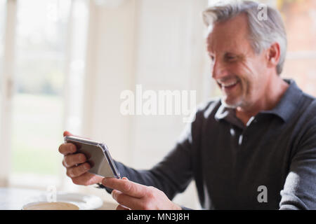Smiling mature man using smart phone Stock Photo