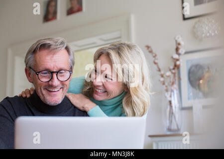 Smiling mature couple using laptop Stock Photo