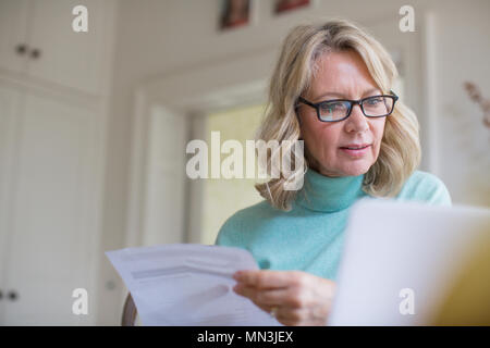 Mature female freelancer working at laptop at home Stock Photo