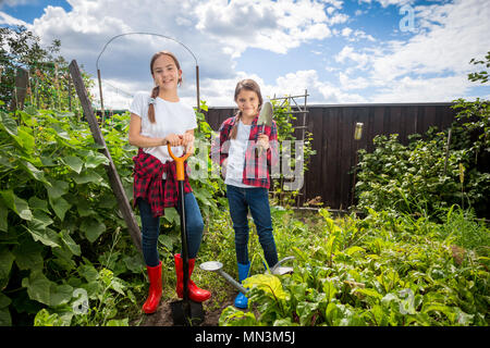 Two teenage girls posing in garden with gardening tools Stock Photo