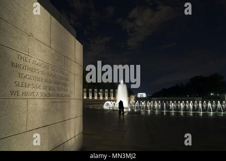 The World War II Memorial at night. A couple paying their respects is silhouetted in the fountain. The inscription on the wall can be read. Stock Photo