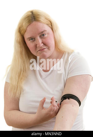 Young caucasian blonde female woman tied up arm with rubber cord and injecting herself in arm with syringe isolated on white background  Model Release: Yes. Property Release: No. Stock Photo