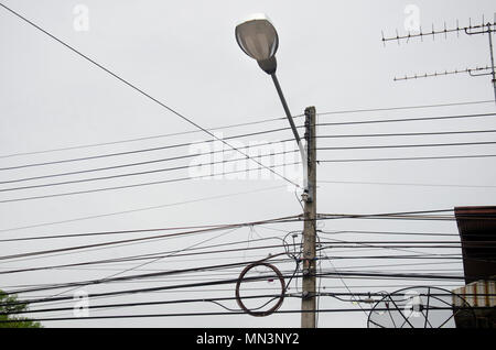 Street lamp and many wires messy with power line cables, transformers and phone lines on old electricity pillar or Utility pole at beside road in Utha Stock Photo