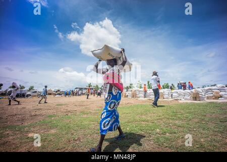 May 7, 2018 - Bidi Bidi, Uganda - A female South Sudanese refugees seen carrying a pack of 50 KG of cassava flour on top of the her head..The Bidi Bidi refugee settlement in northern Uganda near the South Sudanese border is currently the largest refugee camp in the world, hosting over 250,000 South Sudanese refugees fleeing the conflict. The world food program is providing monthly basic food supply for the refugees in the settlement. (Credit Image: © Geovien So/SOPA Images via ZUMA Wire) Stock Photo