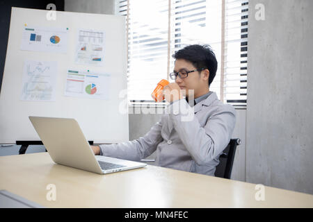 Businessman drinking coffee and working in the office Stock Photo