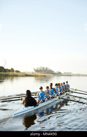 Female rowers rowing scull on sunny lake Stock Photo