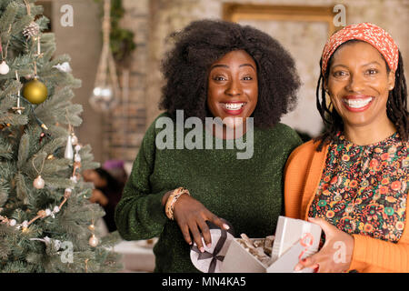 Portrait smiling, enthusiastic mother and daughter opening Christmas gift Stock Photo