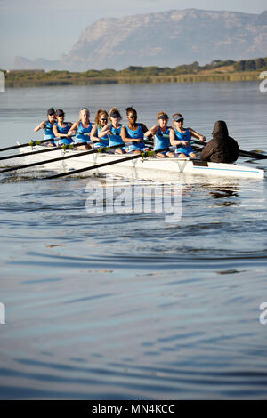 Female rowers rowing scull on sunny lake Stock Photo