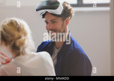 Smiling computer programmer wearing virtual reality simulator glasses Stock Photo