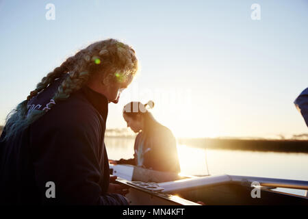Female rowers preparing scull at sunrise lakeside Stock Photo