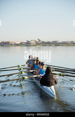 Female rowers rowing scull on sunny lake Stock Photo