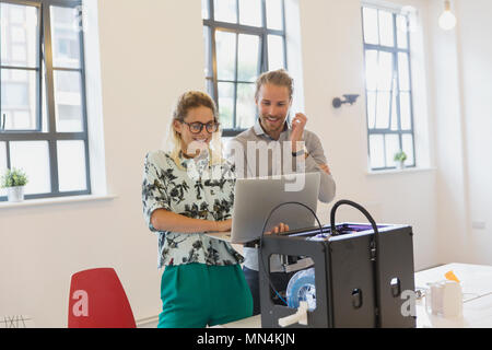 Designers using laptop at 3D printer in office Stock Photo
