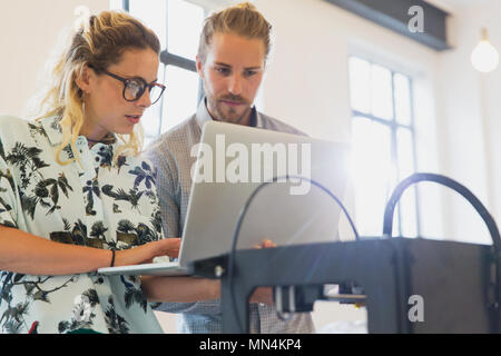 Designers with laptop at 3D printer in office Stock Photo