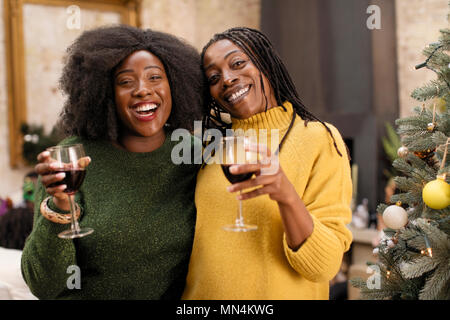 Portrait smiling, happy mother and daughter drinking wine next to Christmas tree Stock Photo
