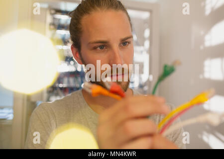 Curious IT technician examining multicolor connection plugs Stock Photo