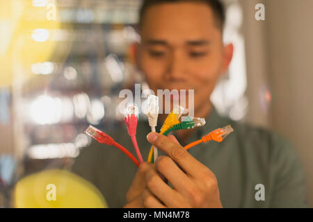 Male IT technician examining multicolor connection plugs Stock Photo