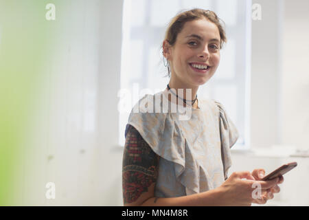 Portrait smiling woman with tattoos texting with smart phone Stock Photo