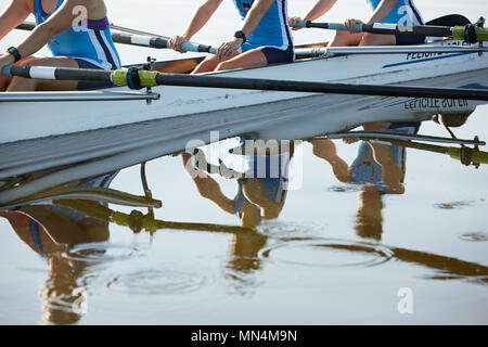 Reflection of female rowers rowing scull on lake Stock Photo
