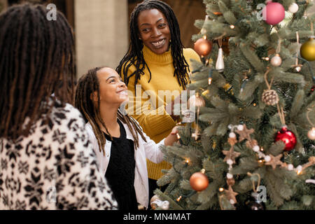 Smiling daughter decorating Christmas tree with mother