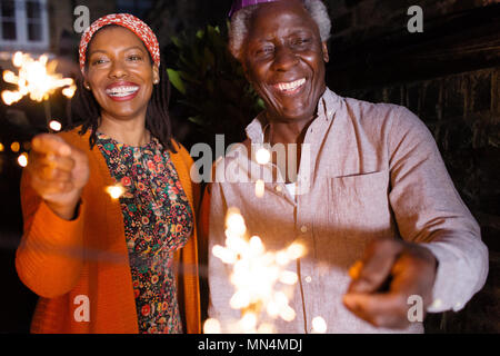 Portrait happy senior father and daughter celebrating with sparklers Stock Photo