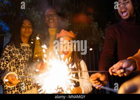 Playful girl with sparkler celebrating with family Stock Photo