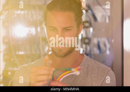 Focused IT technician examining connection plugs in server room Stock Photo