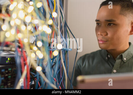 Focused male IT technician examining wires on server panel Stock Photo