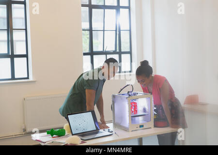 Designers watching 3D printer in office Stock Photo