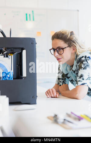 Female designer watching 3D printer in office Stock Photo