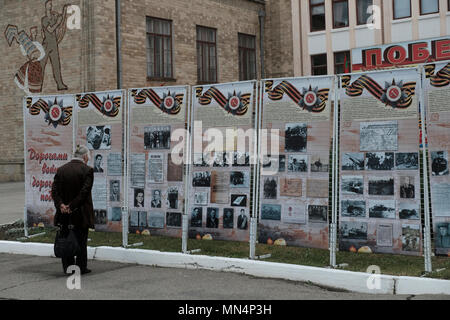 An elderly Transnistrian woman stands next to stands with old photographs of Russians who fought during World War II during the Victory Day on 9th of May which commemorates the victory of the Soviet Union over Nazi Germany in the city of Bender de facto official name Bendery within the internationally recognized borders of Moldova under de facto control of the unrecognized Pridnestrovian Moldavian Republic also called Transnistria (PMR) since 1992. Stock Photo