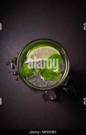Tradition Summer drink mojito with lime and mint in glass on dark stone background