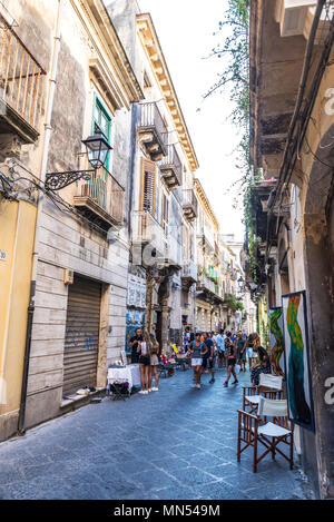 Siracusa, Italy - August 17, 2017: Narrow street with people around in the old town of the historic village of Siracusa in Sicily, Italy Stock Photo