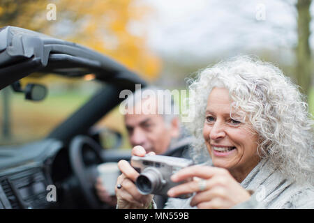 Smiling senior couple using digital camera in convertible Stock Photo