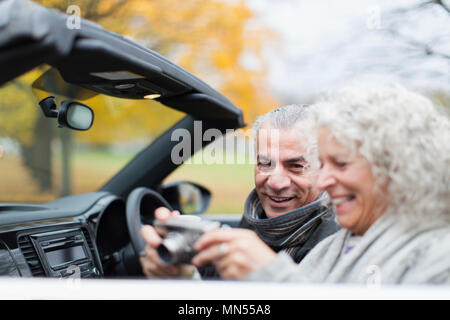 Senior couple using digital camera in convertible Stock Photo