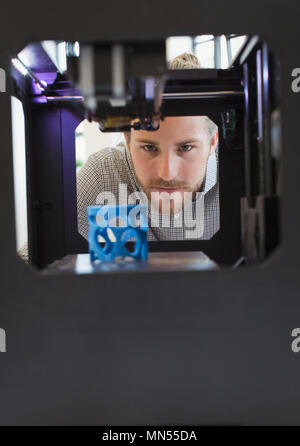 Focused male designer watching 3D printer Stock Photo