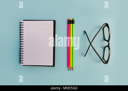 Education notebook pencil and eyeglasses on bright blue background Stock Photo