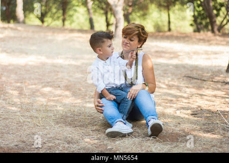 Mother and son sat in the park Stock Photo