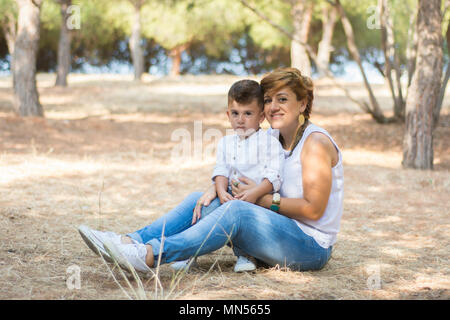 Mother and son sat in the park Stock Photo