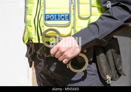 Portrait of a uniformed police officer holding handcuffs Stock Photo