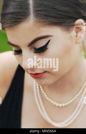 young caucasian woman looking down, closed eyes,pearl necklace Stock Photo